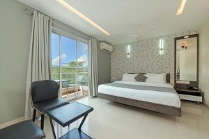 a bedroom with a bed and a chair and a window at Hotel Shoolin Grand in Mangalore