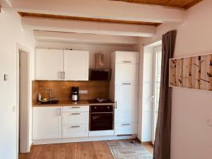 a kitchen with white cabinets and a black oven at Ferienhaus Waldweg in Wienhausen +3 photos