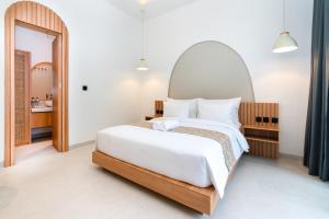 a bedroom with a large white bed and a mirror at Tamanna Villa Uluwatu in Uluwatu