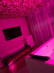 a living room with pink lighting and a tv at Flower spa - Jacuzzi intérieur - T2 in Toulouse