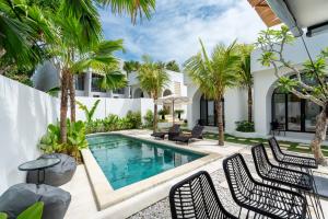an outdoor swimming pool with chairs and palm trees at Tamanna Villa Uluwatu in Uluwatu