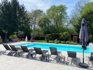a group of chairs and an umbrella next to a pool at Aux Couleurs d'Alsace in Ostwald
