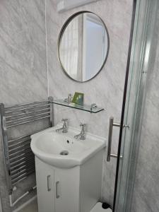 a white bathroom with a sink and a mirror at Shoreline Accommodation in Bournemouth +32 photos