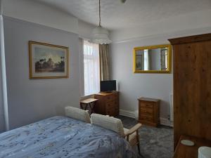 a bedroom with a bed and a desk and a television at Shoreline Accommodation in Bournemouth