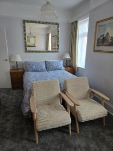 a bedroom with a bed with two chairs and a mirror at Shoreline Accommodation in Bournemouth