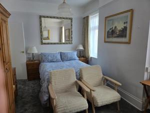 a bedroom with a bed with two chairs and a mirror at Shoreline Accommodation in Bournemouth