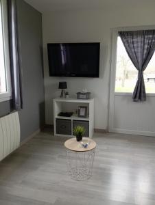 a living room with a table and a flat screen tv at La Petite Maison in Ricarville-du-Val
