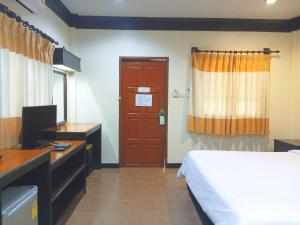 a bedroom with a bed and a desk and a door at เฮือนคำรีสอร์ท บูติค โฮเทล แม่สาย เชียงราย in Chiang Rai
