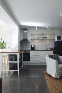 a kitchen with white cabinets and a white couch at Spacious scenic in Stockholm