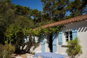 een wit huis met een tafel en stoelen ervoor bij L'écrin de la Pinède in La Barre-de-Monts