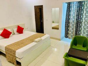 Un dormitorio con una cama con almohadas rojas y una silla en Shree Kesar Inn, en Udaipur