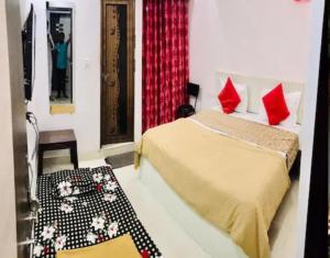 Un dormitorio con una cama con almohadas rojas y un espejo. en Shree Kesar Inn, en Udaipur