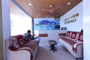 a man sitting on a couch in a waiting room at TEMPLEVIEW RESIDENCy in Srikalahasti