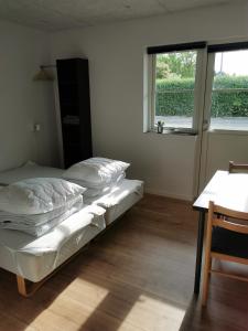 a bedroom with a bed and a table and a window at Ferielejlighed in Nibe