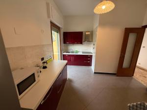 een keuken met rode kasten en een witte magnetron bij Casa Vacanze Terramare in Bogliasco