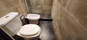 Un baño con un inodoro blanco y un lavabo. en Amplia Casa Centrica, Parrilla, Cochera Privada y Portón Eléctrico para facil acceso, en San Nicolás de los Arroyos 22 fotos más