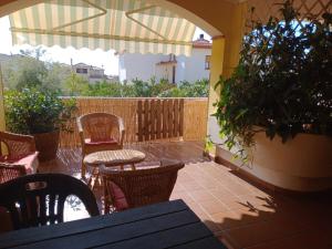 a patio with chairs and tables and an umbrella at Il Sole Baunei by the sea in Santa Maria Navarrese