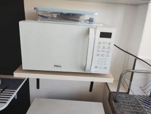 a microwave sitting on a shelf in a kitchen at kitnet08 para 04 pessoas bem localizada garagem in Ourinhos