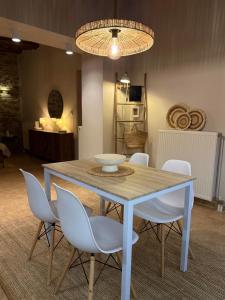 a dining room table with white chairs and a chandelier at Theros in Karistos