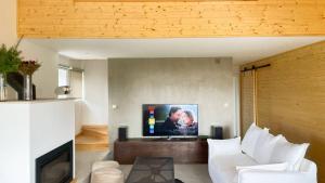 a living room with a white couch and a flat screen tv at Chalet Serra 1506 Geopark S Estrela in Penhas da Saúde