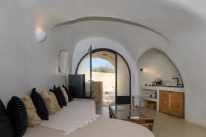 a living room with a white couch and an archway at Anaktos Cave Houses in Santorini