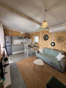 a living room with a blue couch and a kitchen at Lebon Coin Tranquille in Le Tampon