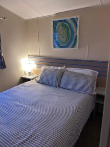 a bedroom with a bed with a blue and white striped blanket at Haven Fleetwood Blackpool Entire home 6 people seaside caravan park in Fleetwood +35 photos