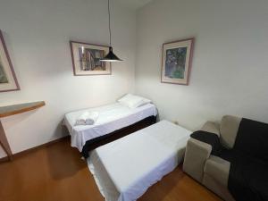 een kleine kamer met 2 bedden en een bank bij Apart Hotel Guinard 1403 - Elegante e Acolhedor in Belo Horizonte +38 foto's