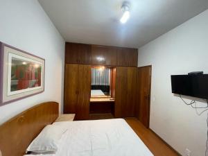 een slaapkamer met een bed en een flatscreen-tv bij Apart Hotel Guinard 1403 - Elegante e Acolhedor in Belo Horizonte