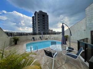 een balkon met een tafel en stoelen en een zwembad bij Apart Hotel Guinard 1403 - Elegante e Acolhedor in Belo Horizonte
