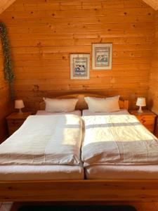 two beds in a log cabin with two lamps at Eichberg Ferienhäuser in Fürstenberg-Havel