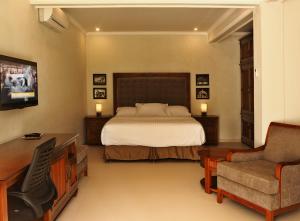 a bedroom with a bed and a desk and a chair at The Gecho Inn Country in Jepara