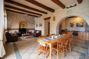 a kitchen and living room with a wooden table and chairs at Hibiscus Xaghra in Xagħra