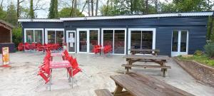 a group of picnic tables and benches in front of a building at Les mobil homes d’oliver rob in Saint-Chéron