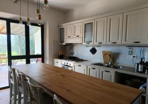 a kitchen with a wooden table and white cabinets at Maremma Design in Manciano