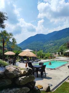 a resort with a pool and tables and umbrellas at Como Lake Villa Galli & Pool in Castelmarte
