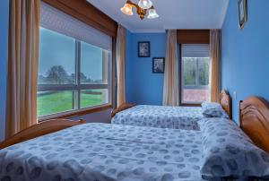 two beds in a bedroom with blue walls and windows at Vivienda Alló in Rois