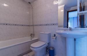 a bathroom with a toilet and a sink and a tub at Vivienda Alló in Rois +33 photos