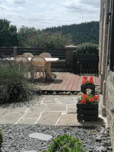 a patio with a table and chairs and flowers at La Maison de Valie in Mercoeur