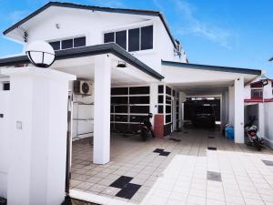 a white house with a garage with motorcycles in it at Miri Homie Homestay 2 in Miri