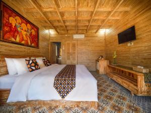 a bedroom with a large bed and a tv at Wisnu Lumbung Uluwatu in Uluwatu
