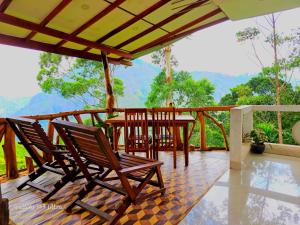 a deck with chairs and a table with a view at Mountain Range Cottage in Ella