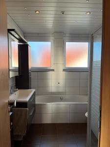 a bathroom with a tub and a sink and two windows at Burgblick Wohnung in Stetten bei Hechingen +21 photos