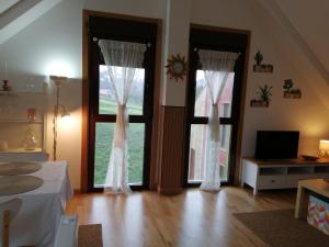 a bedroom with two windows with white curtains and a wooden floor at Ático en Ribeira Ría de Arousa in Ribeira