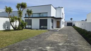 a white house with palm trees and a driveway at Casa Cidade Lagoa - Pool,Jacuzzi family& friends in Rosário-Lagoa