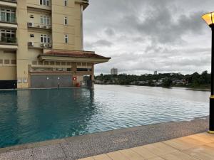a building with a swimming pool next to a river at 4 Pax - Scenic Riverfront Studio B, Kuching City in Kuching
