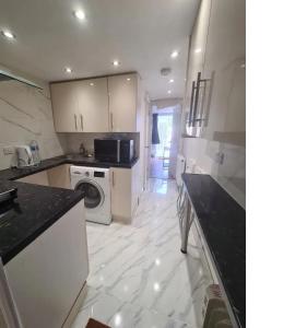 a white kitchen with a washer and dryer in it at 2 bed flat in Heathrow London Free parking in Feltham