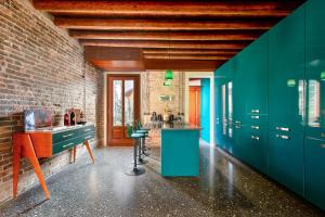 ヴェネツィアにあるGolden Luxe - Glass of Murano luxury apartmentのレンガの壁、緑のキャビネット付きのキッチン