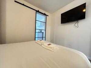 a bedroom with a white bed with a flat screen tv on the wall at E5 Reton T2 chic et confortable au coeur d Epernay in Épernay