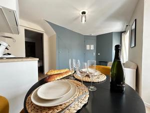 a table with a bottle of wine and glasses on it at E5 Reton T2 chic et confortable au coeur d Epernay in Épernay +16 photos